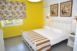 1 dormitorio con cama blanca y pared amarilla en Kos Palace en Tigaki