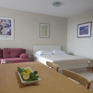 a room with a bed and a table with a bowl of fruit at Apartments Villa Čizmić in Baška Voda