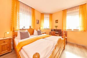 a bedroom with a large bed with yellow walls and windows at Hotel zum dicken Baum in Mayen