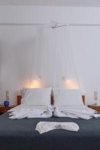 Una cama con sábanas blancas y un par de calzoncillos. en Pension Panorama en Kalamaki