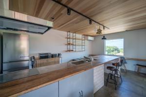 a kitchen with white cabinets and a wooden ceiling at ととのいVilla YAE in Motobu
