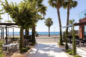a patio with tables and palm trees and the beach at Hotel Royalmar in Cagnes-sur-Mer