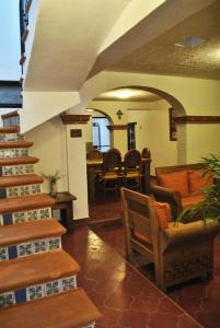uma sala de estar com escadas, cadeiras e mesas em Casa Geranios Tequisquiapan em Tequisquiapan