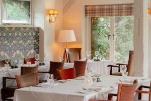 a restaurant with white tables and chairs and a window at Gatton Manor in Ockley