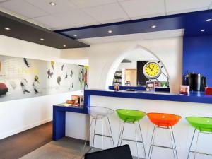 un bar avec trois tabourets et une horloge sur un mur dans l'établissement ibis Styles Vannes Gare Centre, à Vannes