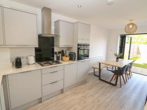 a kitchen with white cabinets and a wooden table at Dune Retreat in Rhosneigr