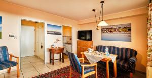 a living room with a table and chairs and a kitchen at "FW Sonnenschein mit Pool, Balkon, Fahrrad und WLAN" in Wangerland