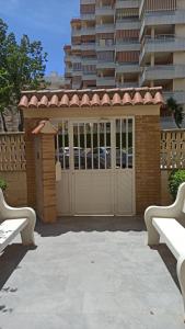 budynek z bramą i dwoma ławkami w obiekcie Joyitas Gandía Beach w mieście Playa de Gandia