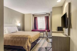 a hotel room with a bed and a flat screen tv at Quality Inn & Suites Grove City-Outlet Mall in Grove City