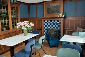 uma sala de jantar com mesas e cadeiras e uma lareira em Blauwe Huis B&B em Nieuwpoort