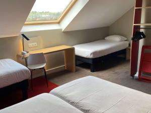 a room with two beds and a desk and a window at Ibis Wavre Brussels East in Wavre