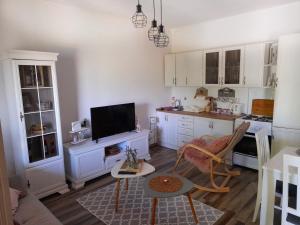 cocina con armarios blancos, mesa y TV en Banjo Rustic House Lake view en Virpazar