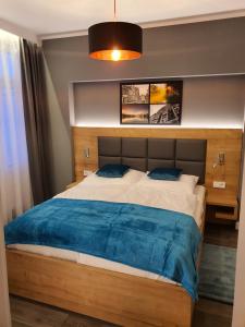 a bedroom with a large bed with a blue blanket at Apartamenty Polonia Mrągowo in Mrągowo