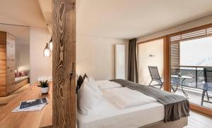 um quarto com uma cama grande e uma varanda em Falkensteiner Hotel & Spa Falkensteinerhof em Valles