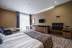 a hotel room with a bed and a flat screen tv at Rudison Hotel & Restaurant in Ternopilʼ