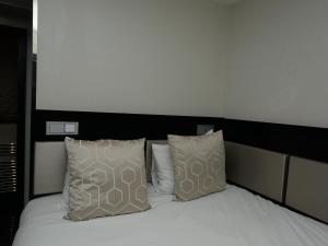 a bedroom with a white bed with two pillows at Great St Helen Hotel in London
