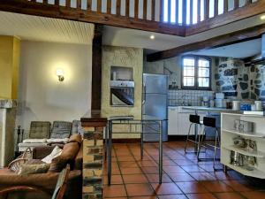 Una cocina con un sofá y una mesa en una habitación. en Élégante maison de maître XVIIIe, jardin clos 500m², nature, proche Puy-en-Velay, 11 pers., cosy & confort - FR-1-582-315, en Arsac-en-Velay