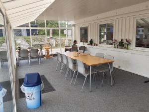 eine Terrasse mit Tischen und Stühlen sowie einem Mülleimer in der Unterkunft Rejkjær Camping Hytter & Lejligheder in Ulfborg
