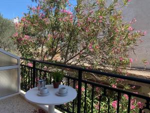 a small white table on a balcony with pink flowers at Maria Studios in Agia Marina Aegina