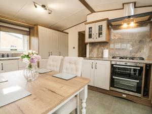 uma cozinha com uma mesa de madeira com um vaso de flores em Ashton Lodge - Sherwood 4 em Carnforth