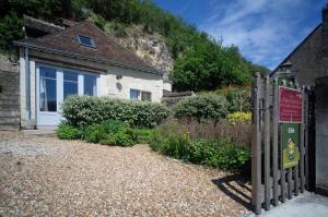 une clôture devant une maison avec une montagne dans l'établissement Gîte semi-troglodytique du Vieux Chai de Trôo, à Trôo