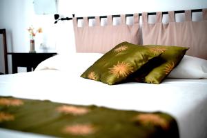 Una cama blanca con dos almohadas verdes. en Hostal Yebisah, en Santa Eulària des Riu