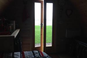 an open door with a view of a green field at River View Log Cabin Pod - 5 star Glamping Experience in Muff