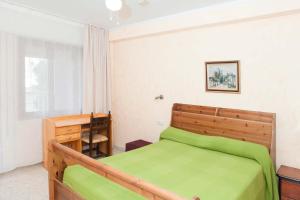 1 dormitorio con cama verde y escritorio en Apartamentos Mirador 2, en Benidorm