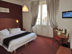ein Hotelzimmer mit einem Bett, einem Schreibtisch und einem Fenster in der Unterkunft Alerion Centre Gare in Metz