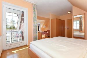 1 dormitorio con cama y ventana grande en Hotel-Pension Störtebeker, en Bensersiel