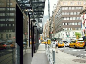 a person walking down a city street with cars at Midtown West Hotel in New York