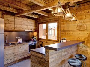 a kitchen with wooden walls and a counter with stools at Chalet Courchevel, 5 pièces, 9 personnes - FR-1-514-20 in le Praz