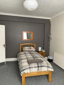 a bedroom with a bed with a gray wall at Bourton House in Rugby