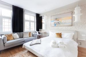 a bedroom with a white bed and a couch at Dom & House - Apartments Old Town Szeroka in Gdańsk
