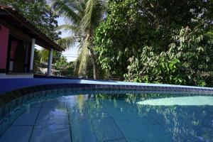 uma piscina em frente a uma casa com árvores em Pousada Coração do Arraial em Arraial d'Ajuda