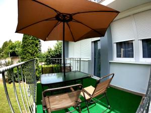 einen Tisch und Stühle auf einem Balkon mit Sonnenschirm in der Unterkunft Dami Apartman in Hajdúszoboszló