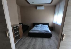 a bedroom with a bed and a desk and a window at Dami Apartman in Hajdúszoboszló