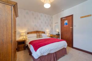 a bedroom with a large bed with a red blanket at The George and Dragon in Dent