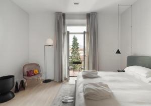 a white bedroom with a large bed and a chair at BB Hotels Aparthotel Collection Il Michelangelo in Florence