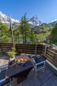 a table and chairs on a patio with mountains in the background at Hotel Petit Palais in Breuil-Cervinia