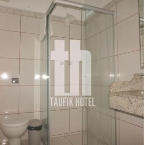 a bathroom with a toilet and a glass shower stall at Taufik Hotel in Rio Grande