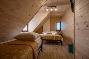 two beds in a small room with wooden walls at Apartamenty na Polnej in Leśnica