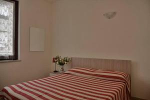 a bedroom with a bed with a striped blanket at App. a 30mt dal mare in Pietra Ligure