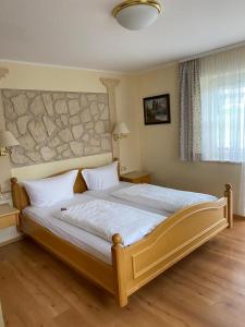 a bedroom with a large bed with a stone wall at Wertacher Hof in Oy-Mittelberg