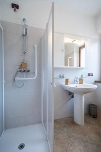 ein weißes Bad mit einem Waschbecken und einer Dusche in der Unterkunft Marangon Apartments in Sùtrio