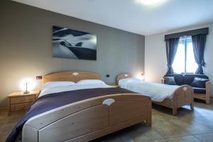 sypialnia z 2 łóżkami i krzesłem w obiekcie Marangon Apartments w mieście Sùtrio