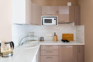 eine weiße Küche mit einer Spüle und einer Mikrowelle in der Unterkunft NasutkiPro Apartments on Fontanka in Sankt Petersburg
