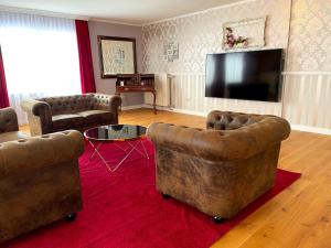 a living room with two couches and a flat screen tv at Seehotel Louise in Gransee