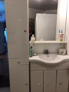 ein weißes Badezimmer mit einem Waschbecken und einem Spiegel in der Unterkunft Maison d'Argonne in Brécy-Brières