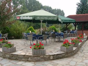 patio ze stołami, krzesłami i parasolem w obiekcie Hotel Landhaus Greene w mieście Einbeck